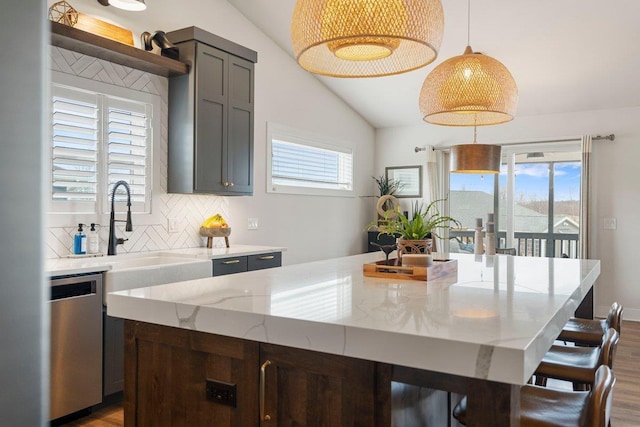 kitchen featuring dark wood-type flooring, dishwasher, a sink, and vaulted ceiling