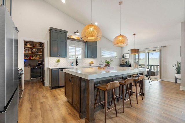 kitchen with light wood finished floors, stainless steel appliances, tasteful backsplash, a kitchen bar, and a kitchen island