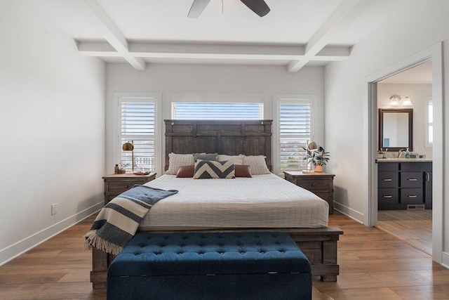 bedroom featuring beamed ceiling, wood finished floors, baseboards, and ensuite bathroom