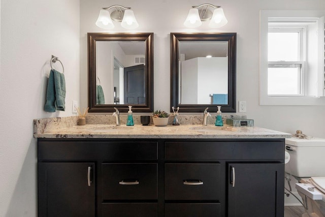 bathroom featuring visible vents, a sink, double vanity, and toilet