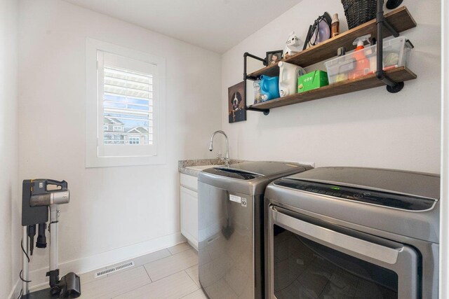 laundry area featuring washing machine and clothes dryer, a sink, baseboards, visible vents, and cabinet space