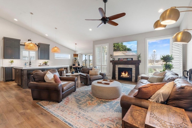 living room with recessed lighting, lofted ceiling, wood finished floors, a ceiling fan, and a fireplace