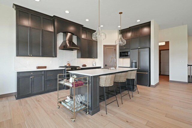 8437 Creek View Ln, Mount Pleasant, WI 53406 - kitchen featuring built in appliances, decorative backsplash, wall chimney exhaust hood, and light wood-style flooring