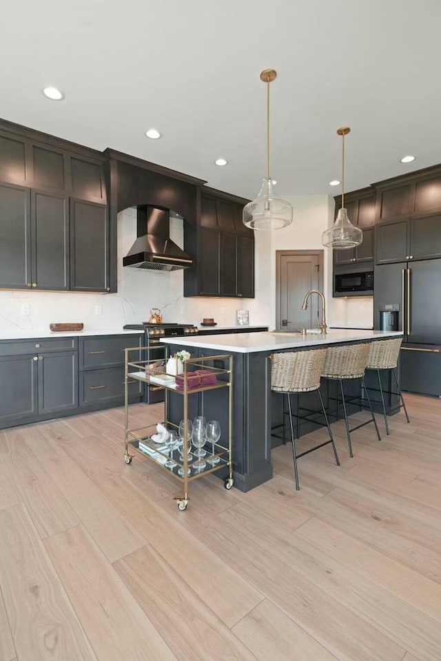 8437 Creek View Ln, Mount Pleasant, WI 53406 - kitchen featuring light countertops, light wood-style floors, wall chimney exhaust hood, built in appliances, and a breakfast bar area