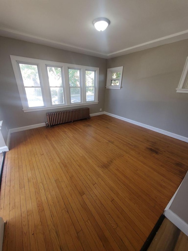 empty room featuring radiator, hardwood / wood-style flooring, and baseboards