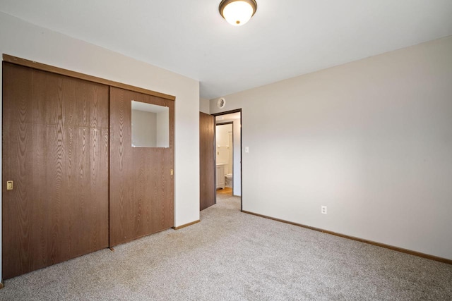 unfurnished bedroom with a closet, baseboards, and light carpet