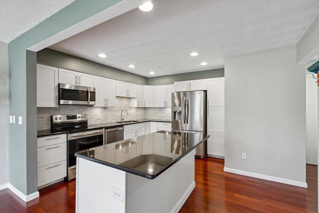 kitchen featuring a sink, stainless steel appliances, baseboards, decorative backsplash, and dark wood-type flooring