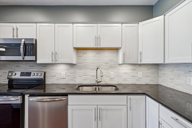 kitchen with a sink, white cabinetry, dark stone countertops, and stainless steel appliances