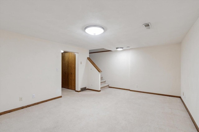 finished below grade area with stairs, baseboards, visible vents, and carpet