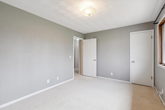 unfurnished bedroom featuring baseboards and light carpet