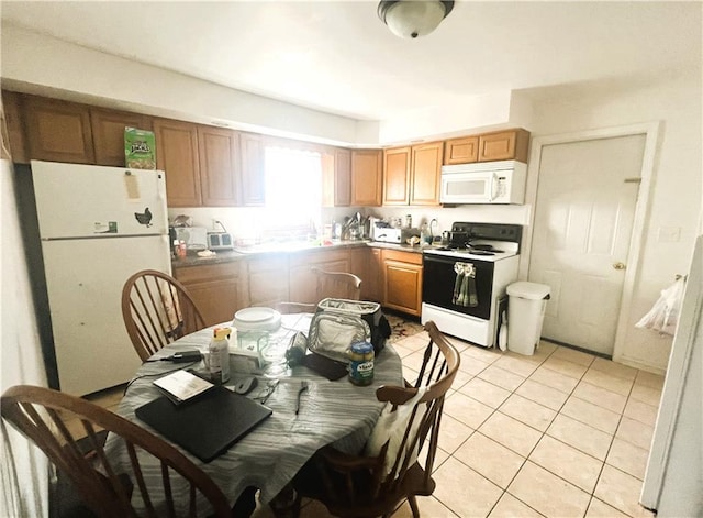 kitchen with brown cabinetry, white appliances, and light tile patterned flooring
