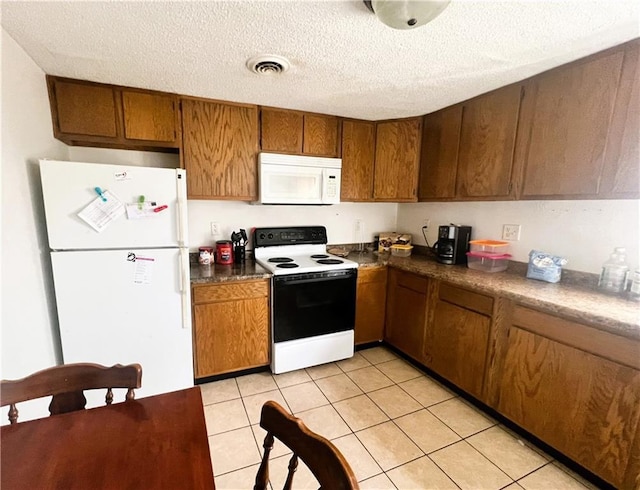 kitchen featuring brown cabinets, light tile patterned flooring, a textured ceiling, and white appliances