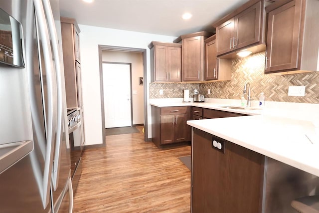 4365 Lakeland Dr, Oshkosh, WI 54904 - kitchen featuring a sink, light countertops, light wood-style flooring, backsplash, and appliances with stainless steel finishes