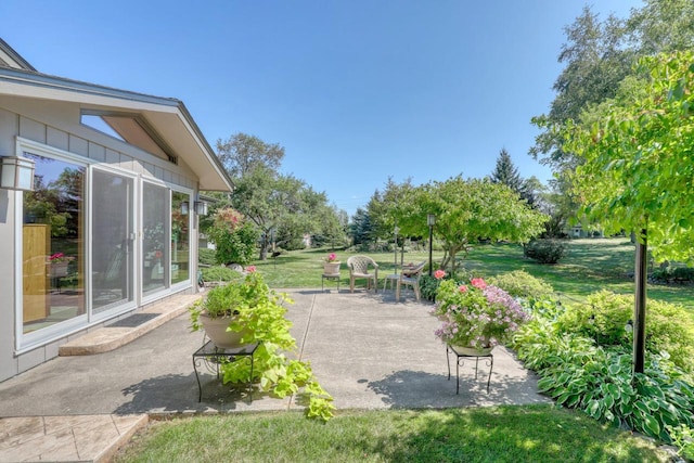 view of property's community featuring a lawn and a patio