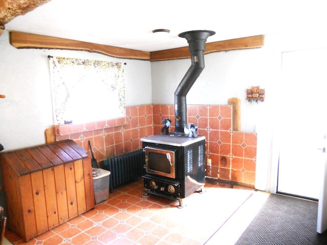room details with beamed ceiling, a wood stove, and wainscoting