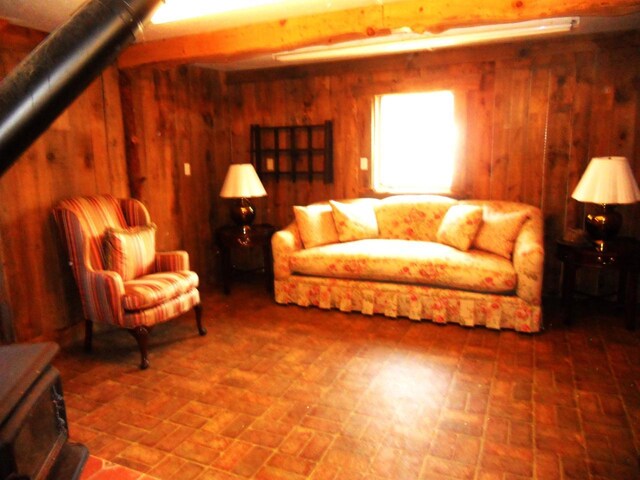 living room featuring wood walls, a wood stove, and brick patterned floor