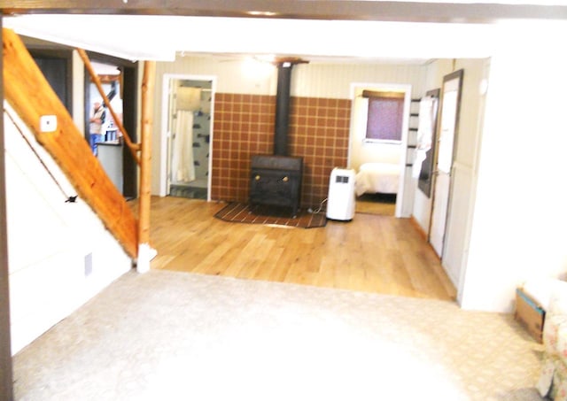 unfurnished living room featuring stairway, a wood stove, and wood finished floors