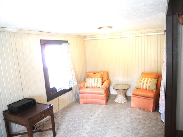 sitting room featuring carpet floors and wood walls