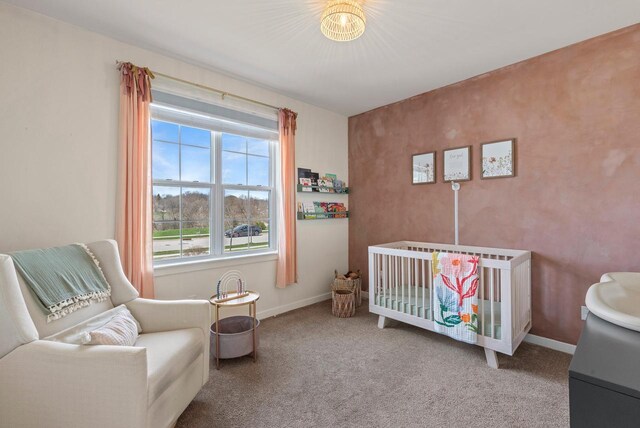 bedroom featuring carpet floors, baseboards, and a crib