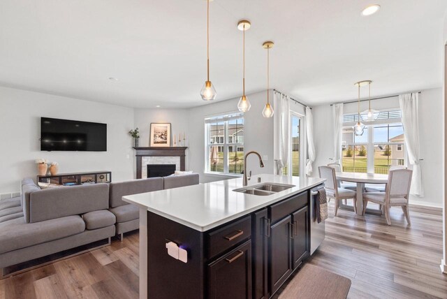 kitchen with light countertops, a stone fireplace, a sink, and wood finished floors