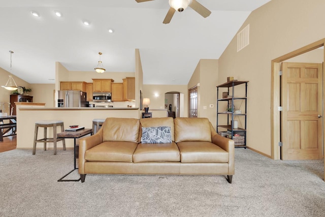 living room featuring arched walkways, visible vents, a ceiling fan, and light carpet