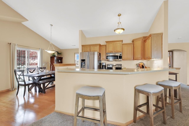 kitchen featuring arched walkways, a sink, appliances with stainless steel finishes, and a kitchen bar