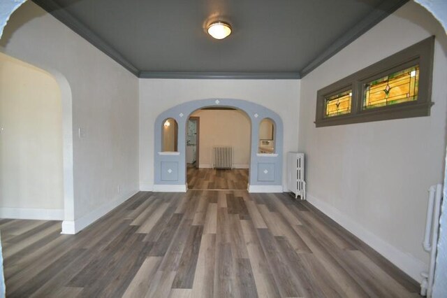 3736 E Edgerton Ave, Cudahy, WI 53110 - empty room with arched walkways, radiator heating unit, wood finished floors, and baseboards