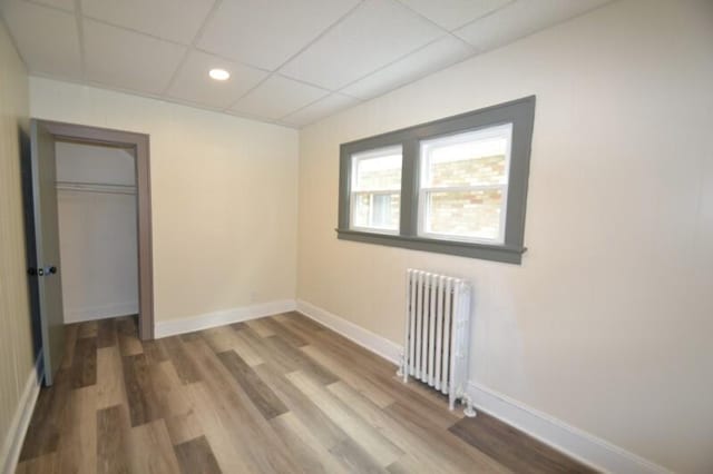 3736 E Edgerton Ave, Cudahy, WI 53110 - unfurnished bedroom with baseboards, radiator heating unit, wood finished floors, and a drop ceiling