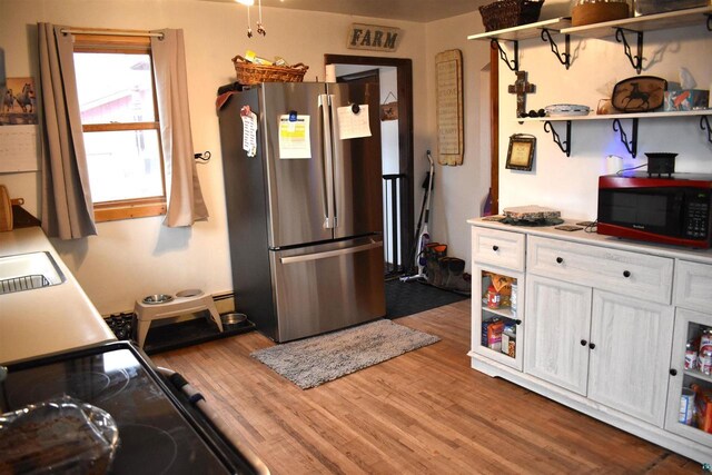 71435 Range Line Rd, Iron River, WI 54847 - kitchen featuring white cabinets, open shelves, wood finished floors, freestanding refrigerator, and black electric range oven