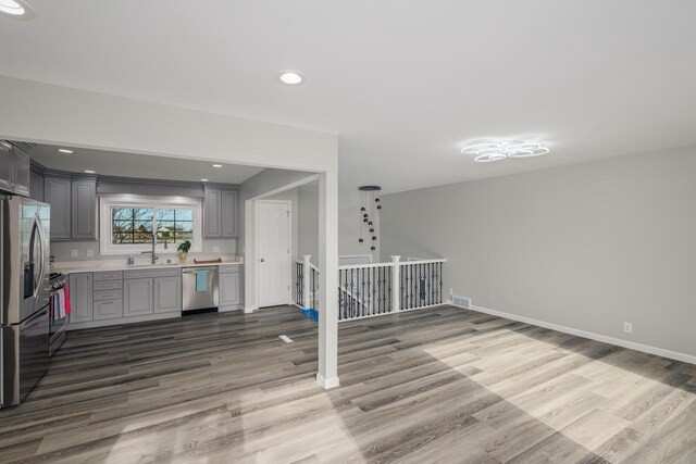 2941 Chapel Ln, Mount Pleasant, WI 53406 - unfurnished living room with visible vents, baseboards, wood finished floors, and a sink
