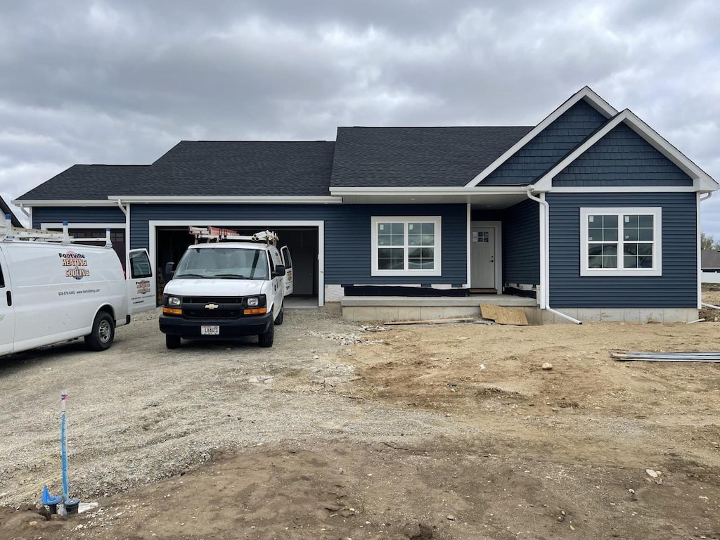 view of front of house with covered porch, roof with shingles, and a garage
