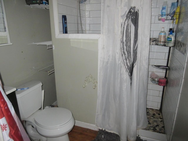 full bathroom with toilet, a stall shower, wood finished floors, and baseboards