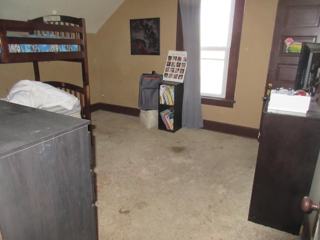 carpeted bedroom featuring lofted ceiling and baseboards