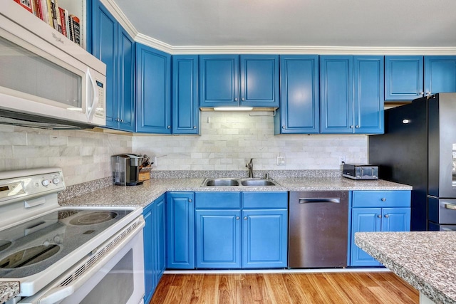 kitchen featuring blue cabinetry, a sink, white appliances, and light wood-style floors