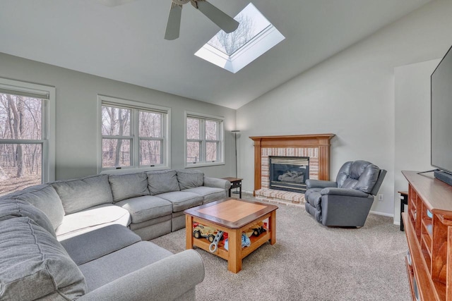 carpeted living room featuring a skylight, a fireplace, ceiling fan, and high vaulted ceiling