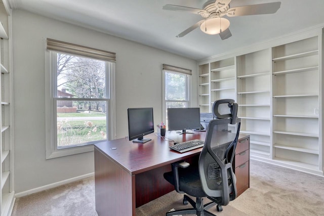 office area featuring a ceiling fan, baseboards, light carpet, and built in features