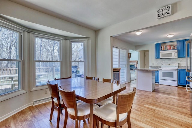 dining room featuring plenty of natural light, baseboards, visible vents, and light wood-style floors