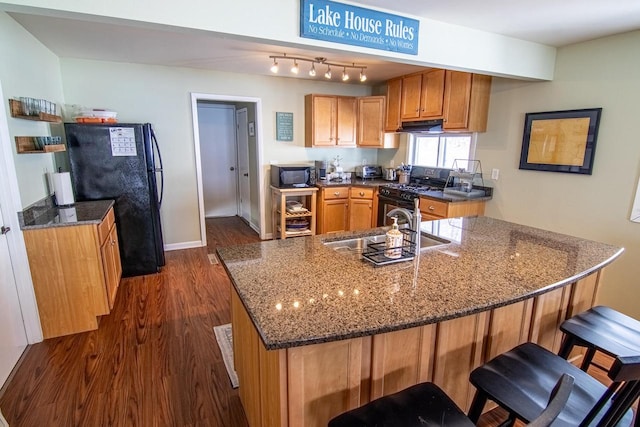 N4142 Sleepy Hollow Rd, Cambridge, WI 53523 - kitchen featuring brown cabinetry, dark stone counters, dark wood-style flooring, and black appliances