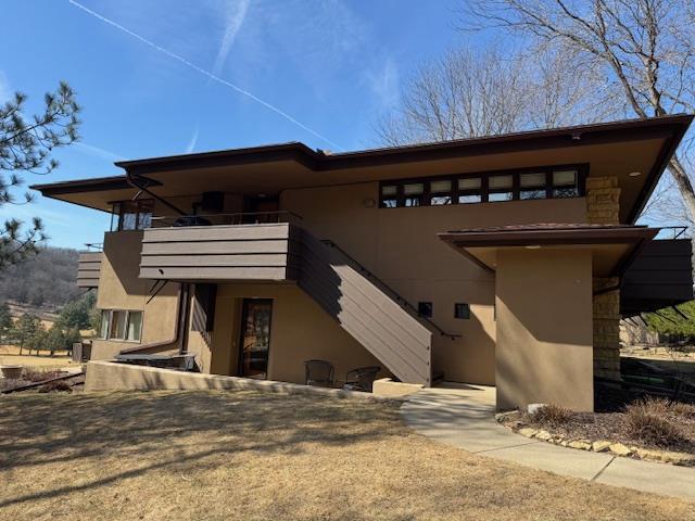 back of house featuring a balcony, stairs, and stucco siding