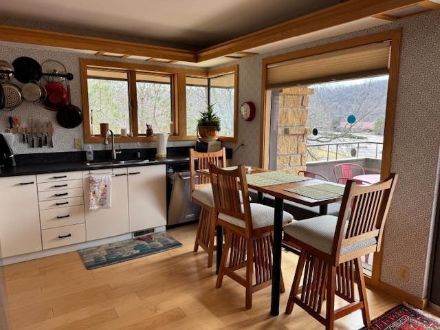 dining space with wallpapered walls, light wood-style flooring, and crown molding