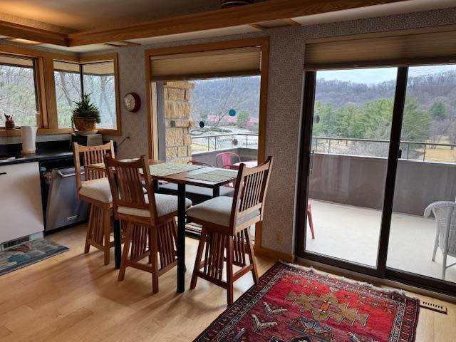 dining area with light wood finished floors and wallpapered walls