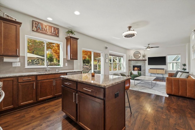 1549 Cambridge Ct, Hubertus, WI 53033 - kitchen with dark wood finished floors, backsplash, a warm lit fireplace, a sink, and ceiling fan