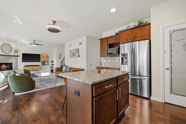 1549 Cambridge Ct, Hubertus, WI 53033 - kitchen featuring dark wood-style floors, light stone counters, stainless steel fridge with ice dispenser, black microwave, and a fireplace
