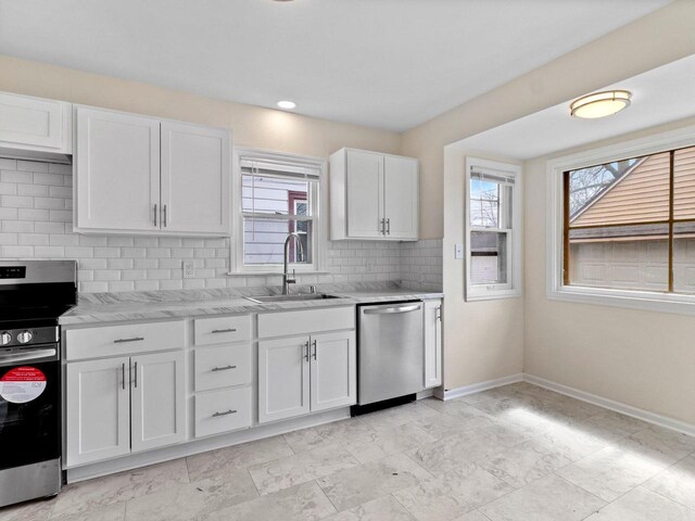 7509 W Burleigh St, Milwaukee, WI 53210 - kitchen with backsplash, a sink, baseboards, appliances with stainless steel finishes, and white cabinetry