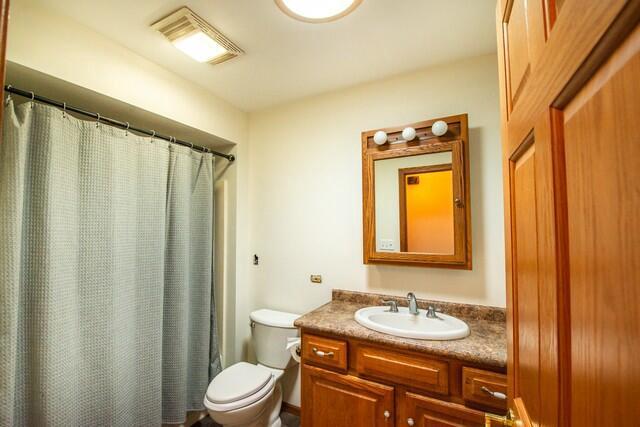 9506 296th Ave, Salem, WI 53168 - full bath featuring a shower with curtain, visible vents, vanity, and toilet