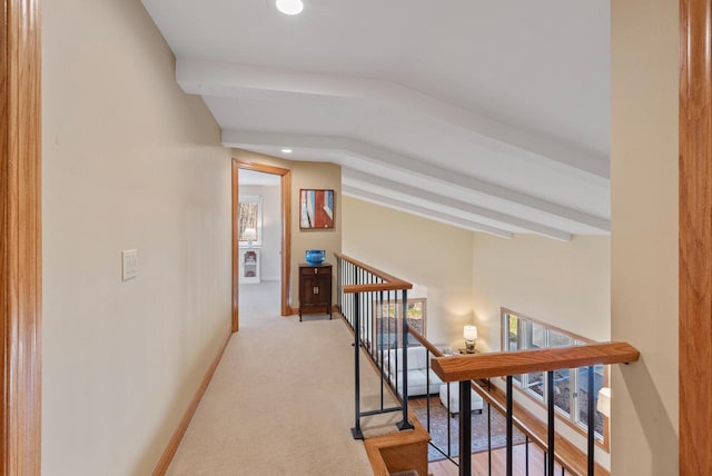 corridor with baseboards, vaulted ceiling with beams, light colored carpet, and an upstairs landing