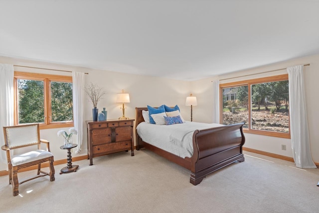 bedroom featuring light carpet, multiple windows, and baseboards
