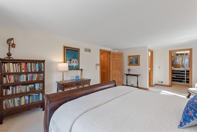 carpeted bedroom featuring baseboards, visible vents, and a walk in closet