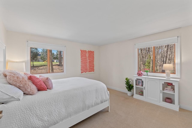 bedroom featuring light colored carpet and baseboards