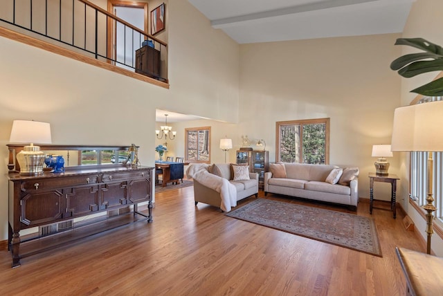 living room with wood finished floors, a towering ceiling, and a notable chandelier